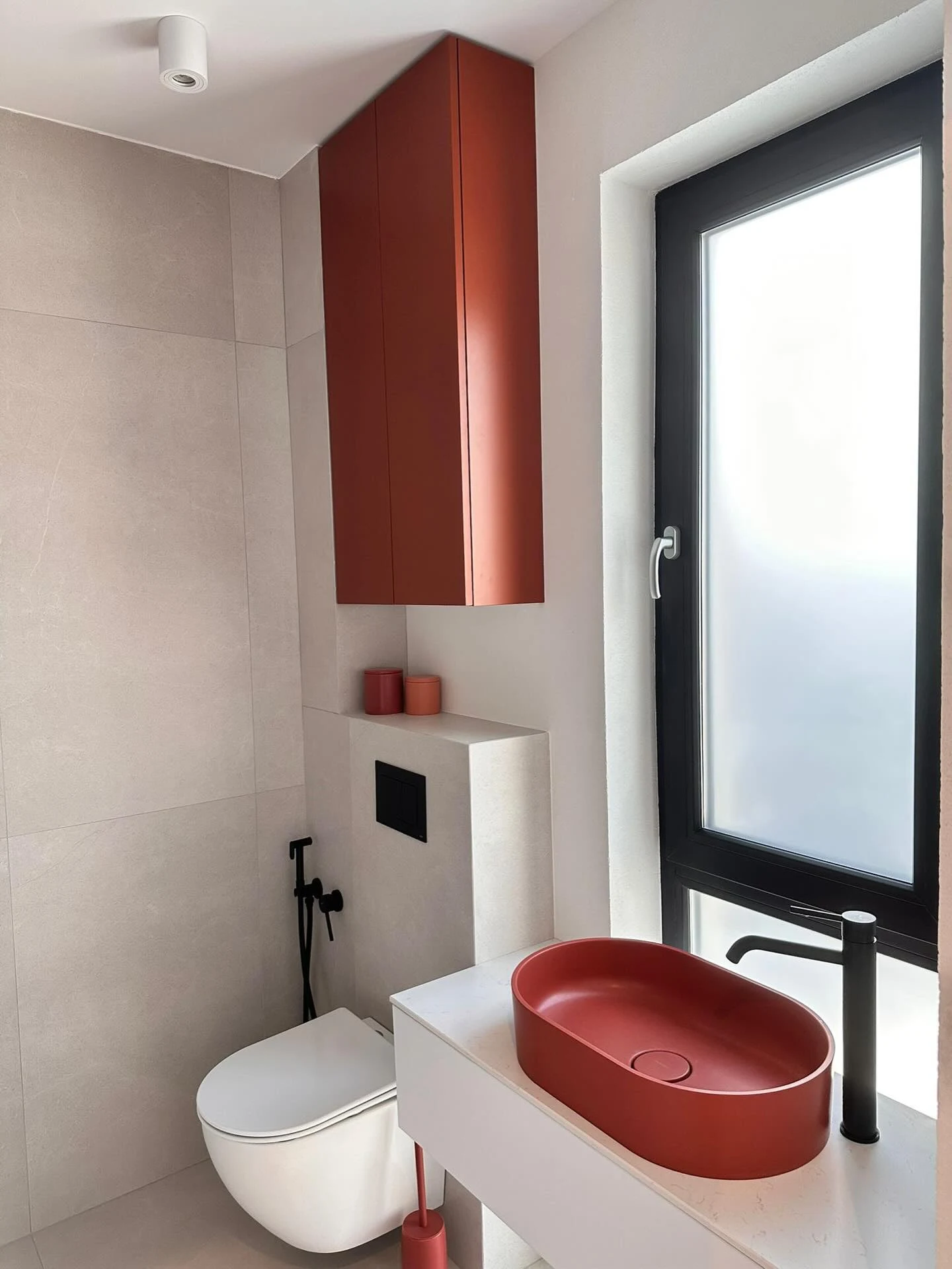 Mobilier pentru baie în tonuri de teracotă, lavoar oval și corpuri suspendate