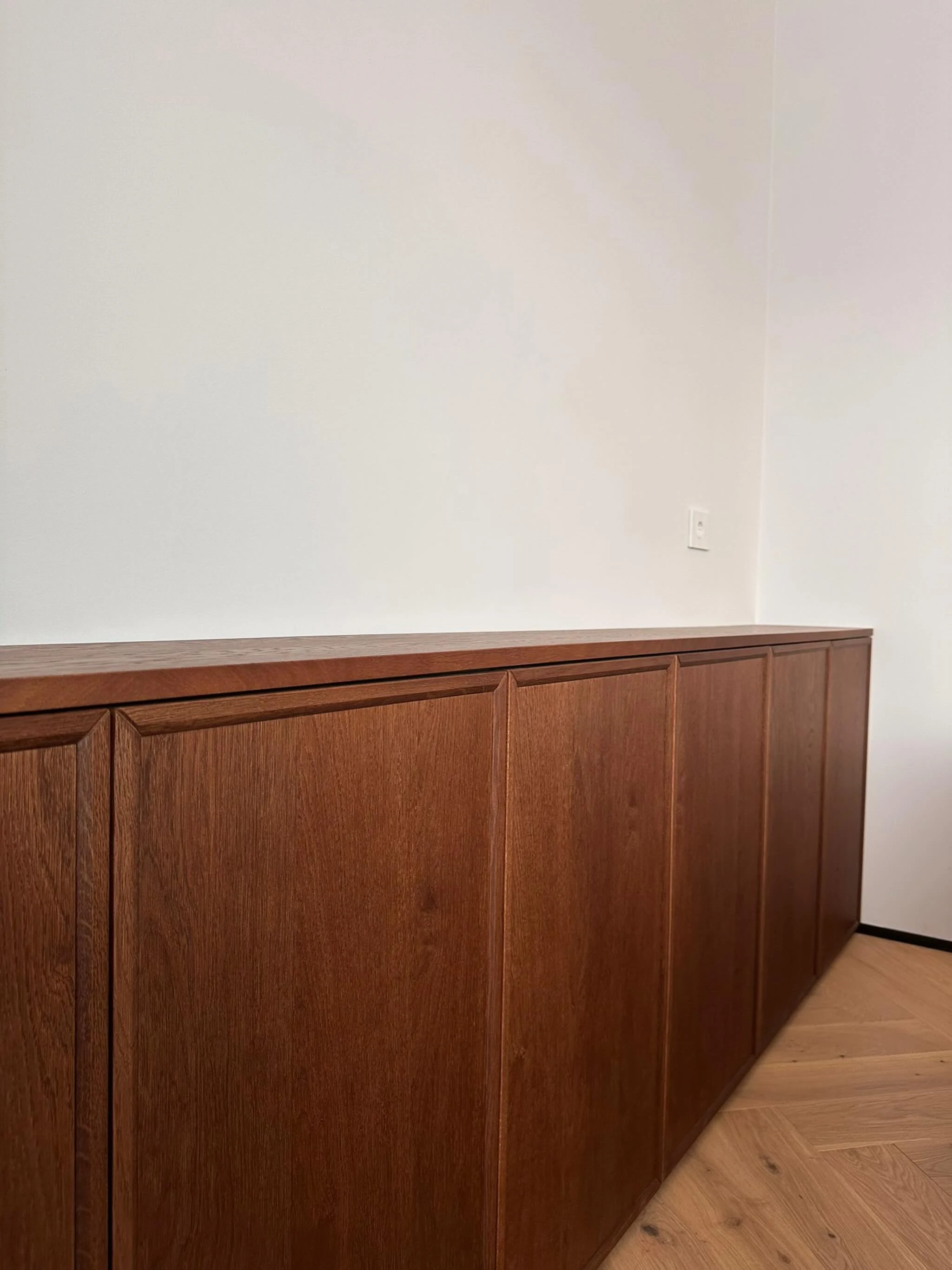 Fronturi de mobilier din lemn cu ramă și panouri, lângă parchet în spic